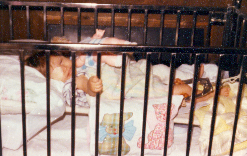 Young 2 year old in crib.  Leg extended in a cast with traction.  Eye patch worn over eye.  